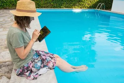 Focused woman in straw hat sitting at poolside