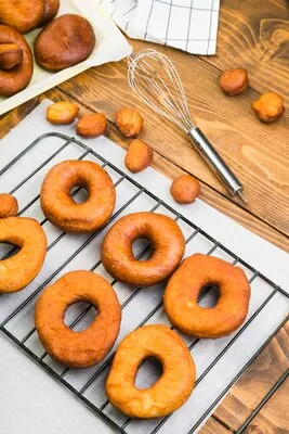 High angle view of tasty homemade donuts on tray near whisk on wooden textured table
