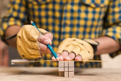 Close-up of a male carpenter's hand making measurement on wooden block