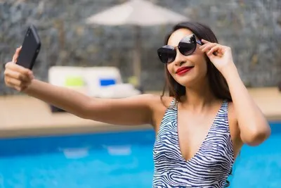 Portrait beautiful asian woman using mobile phone around outdoor swimming pool