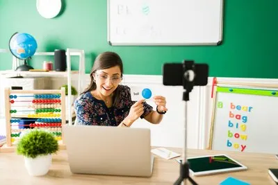 Vocabulary lessons. Happy female teacher using flashcards to teach the letters and the alphabet to preschool little kids during a virtual class
