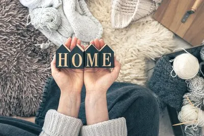 Decorative word home in female hands on a background of knitted items top view