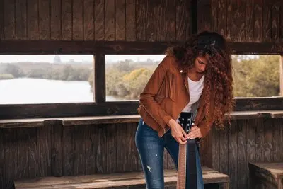 Front view woman tuning a guitar