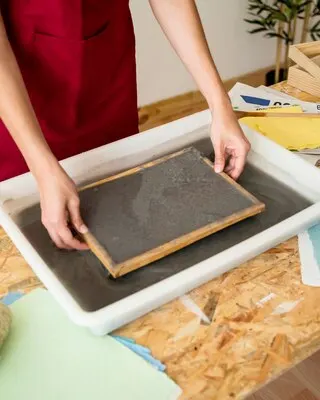 Elevated view of woman's hand removing mold from tray on desk