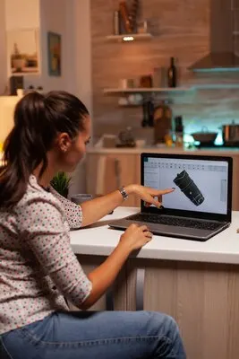 Engineer pointing at turbine project on laptop while working on laptop during night time industrial ...