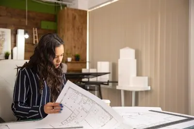 Young woman architect who controls the sketches of the real estate project. Cozy work place