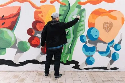 Rear view of a man making graffiti with spray can on wall
