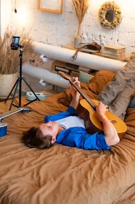 Teenage boy recording music with his guitar at his home studio