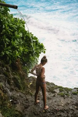 young woman under a waterfall on a cliff unity with nature