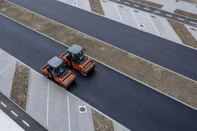 Aerial view of orange vibratory asphalt roller compactor on a new pavement