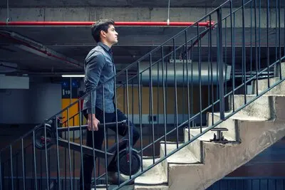 Successful businessman climbing stairs of building going to work office while holding electric scooter for commuting