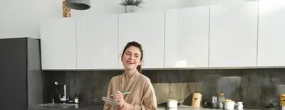 Vertical shot of young woman writing down food ideas creating new meal writing down grocery list or