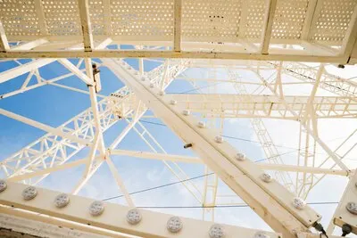 Close-up of white ferris wheel against blue sky