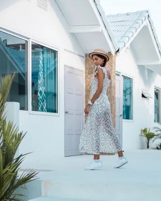 Positive calm woman in light summer dress, straw hat, tropical location