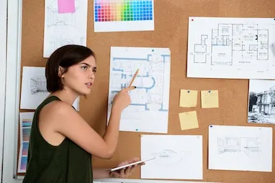 Young beautiful businesswoman standing near desk with drawings