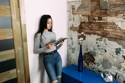 Stylish young woman leans to the wall reading journal