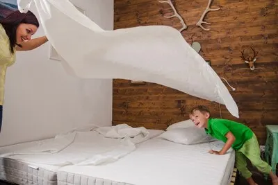 Woman playing with child while making bed