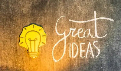 Yellow paper cutout light bulb with written text on blackboard