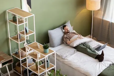 Man laying on bed listening to music