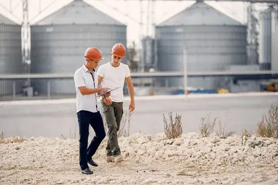 Engineers in  helmets standing by the factory