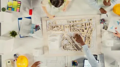 Top down view of developers and architects in business meeting reviewing blueprints and structural