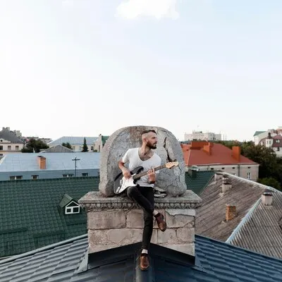 Front view of male musician playing electric guitar on roof top