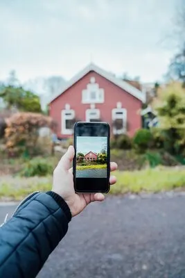 Vertical closeup shot of a person taking a photo of a traditional red house