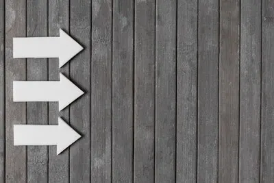 White arrows on wooden background