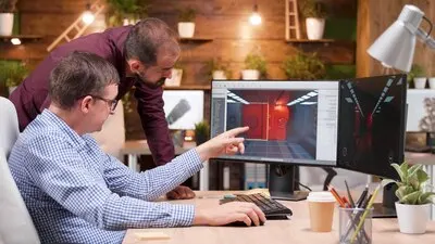 Graphic designer in gaming industry talking detail with his colleague analyzing 3d design level explaining production creative ideas. Game creators working at videogame illustration in company office