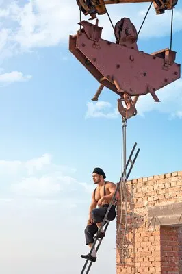 Resting a bit. Hunky shirtless builder sitting on a ladder at the skyscraper under construction