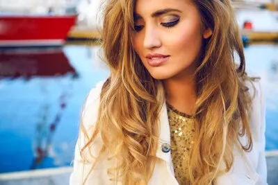 Outdoor fashion portrait of beautiful woman with perfect skin, dreaming alone and looking on the floor. and enjoy her thoughts , have natural make up, posing at sea port.