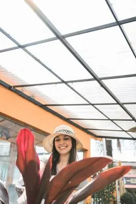 Close-up of red leaves in front of happy woman standing in greenhouse