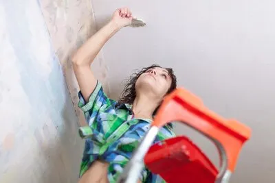 girl paints ceiling  at home