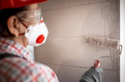 Back view of female construction worker with helmet and paint roller