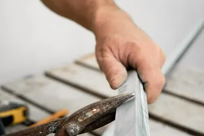 Craftsman cuts steel profiles for drywall, close-up, selective focus. Preparing for the installation of the frame of the ceiling profile system. Renovation and renovation