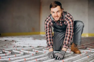 Service man instelling house heating system under the floor