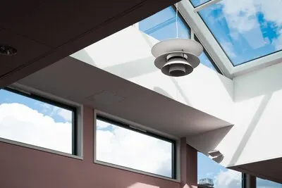 Low angle shot of a lamp hanging inside a building with a glass ceiling