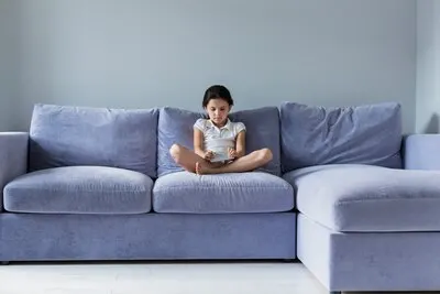 Lovely little girl with smartphone on the sofa