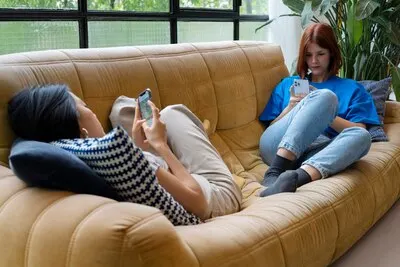 Full shot women laying on couch with smartphones