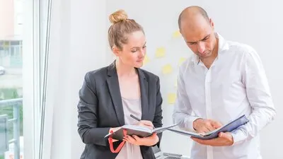 Male and female businesspeople looking at schedule in diary