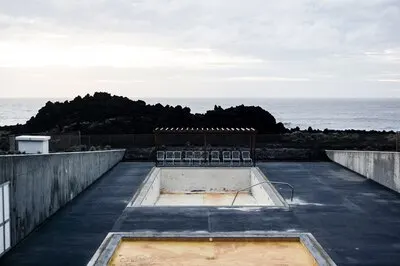 Empty pool with chairs  near the cliff and a sea