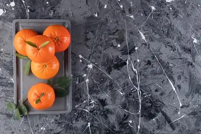 Fresh tangerine on a wooden plate , on the mixed table.