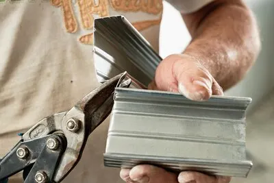 Cutting steel profiles by a master, close-up, selective focus. Preparing for the installation of the frame of the ceiling profile system of drywall. Renovation and renovation industry