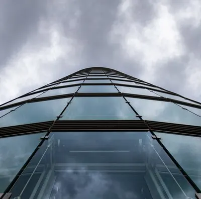 Low angle shot of a high rise building in a glass facade under the storm clouds